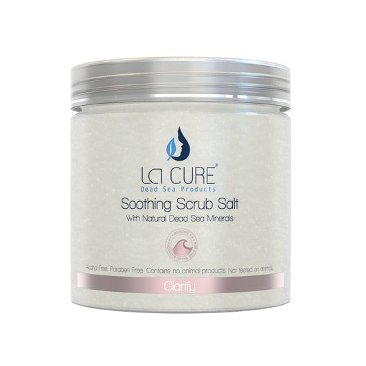 A jar of LA CURE Soothing Scrub Salt with a silver lid and a light gray label featuring blue and pink branding details, set against a plain white background.